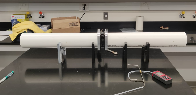Photo of the fan efficiency test rig: a long PVC duct with the fan unit and supports on a lab bench