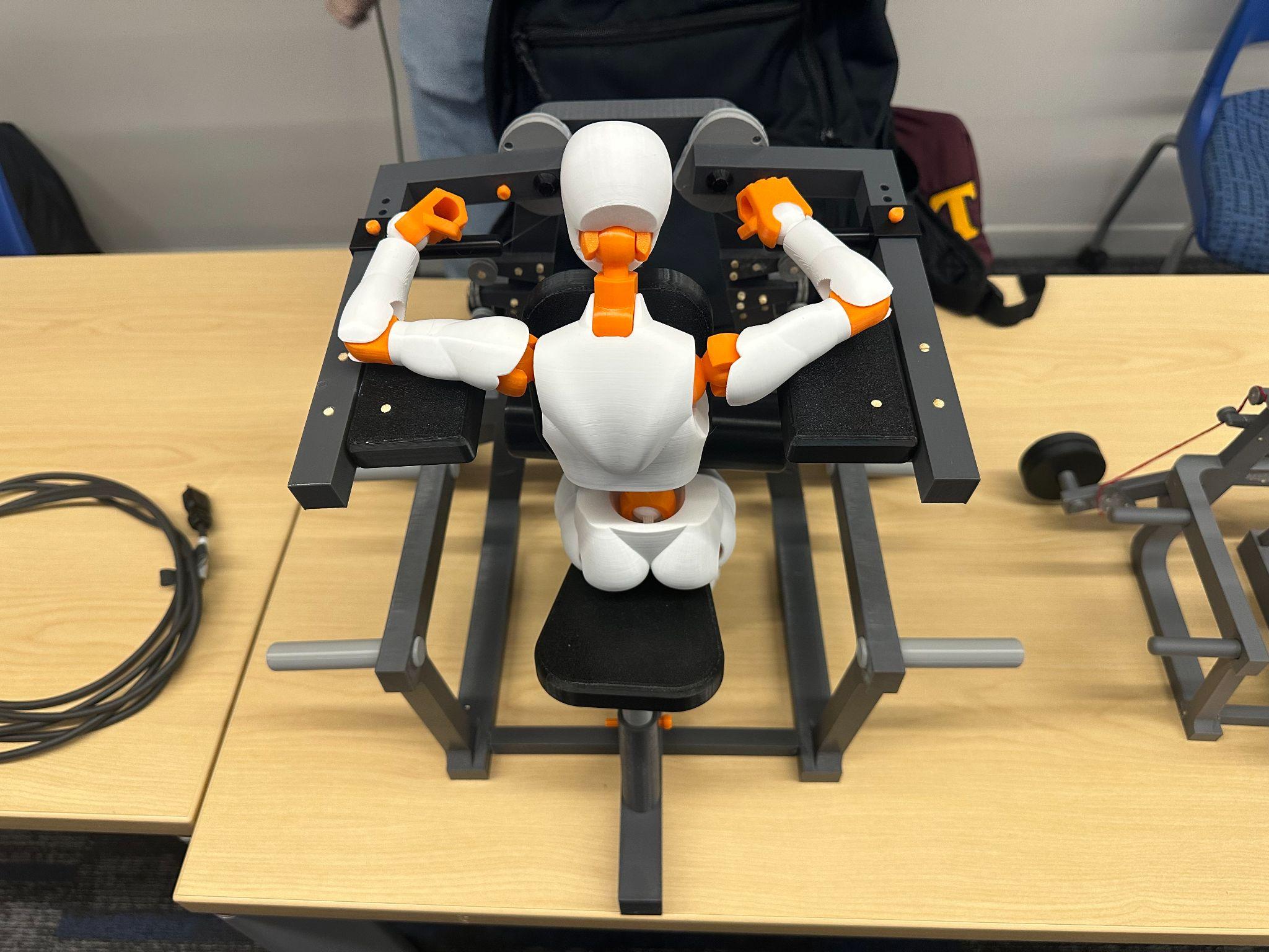 Final 3D-printed rendition of the latissimus dorsi adduction machine with an articulated test figure seated in position