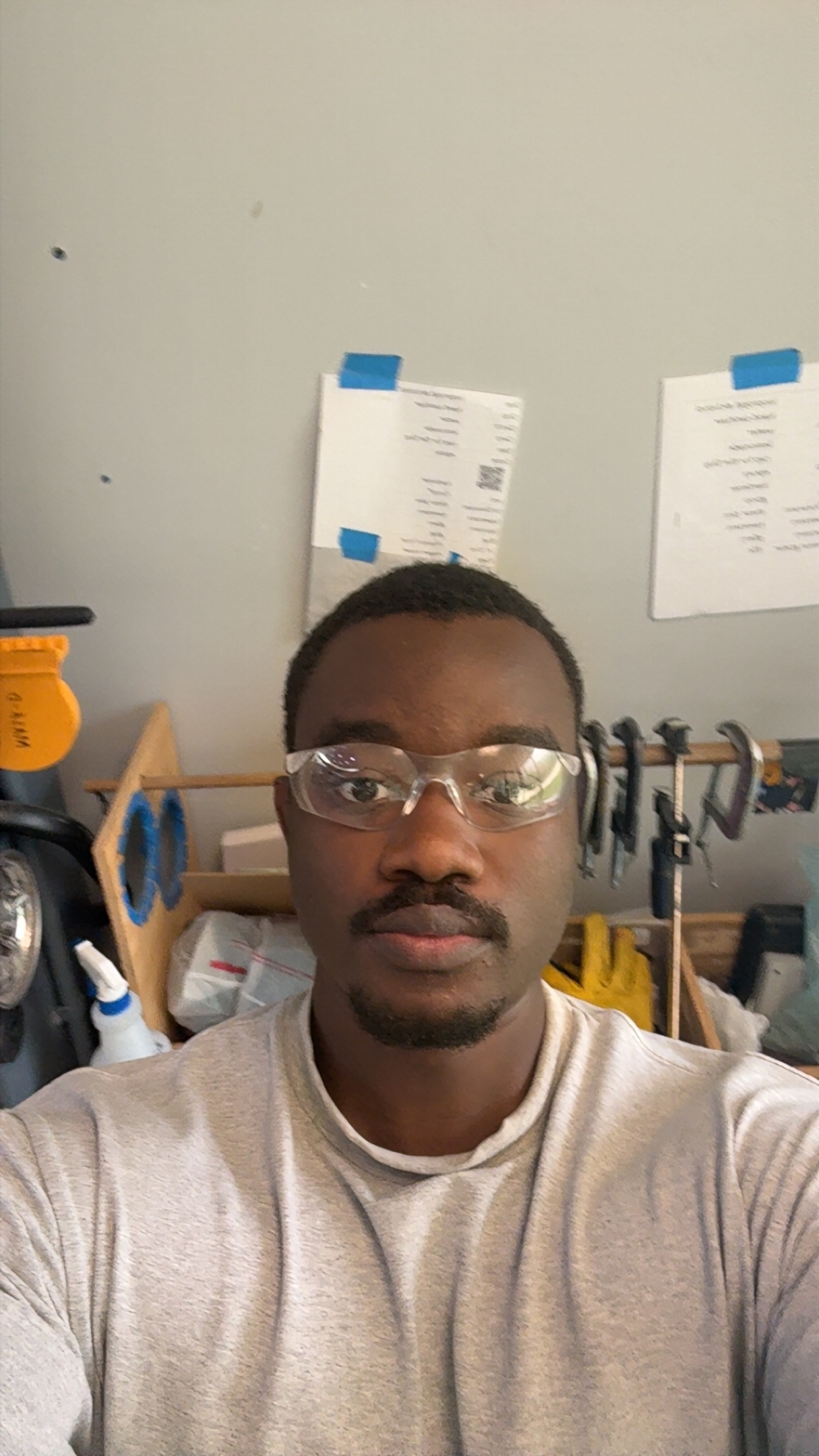 Jidechukwu Owo in safety glasses at his garage workbench, clamps and prototyping tools behind him